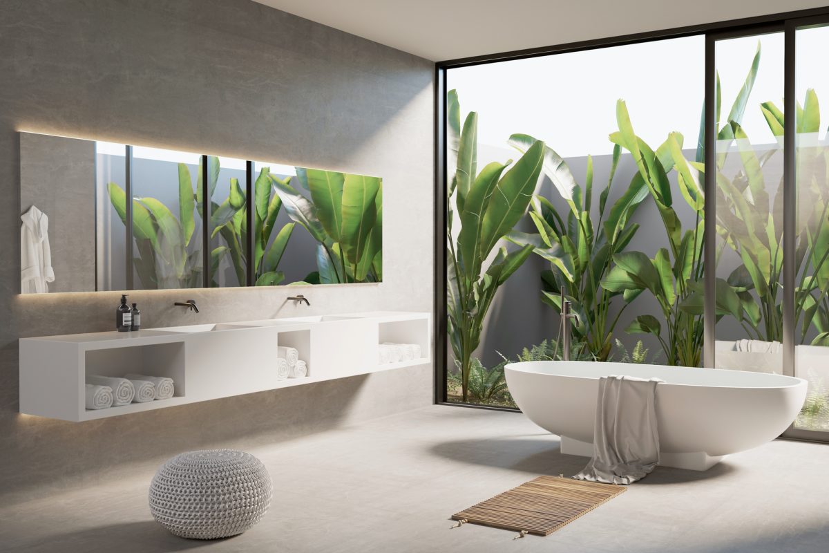 3d render of a modern  concrete bathroom with a bathtub and a view to a palm and banana trees garden